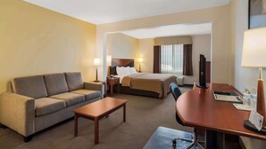 A hotel room with a sofa, a bed, a desk, and a television. - Quality Inn & Suites Chambersburg Northeast (Chambersburg)