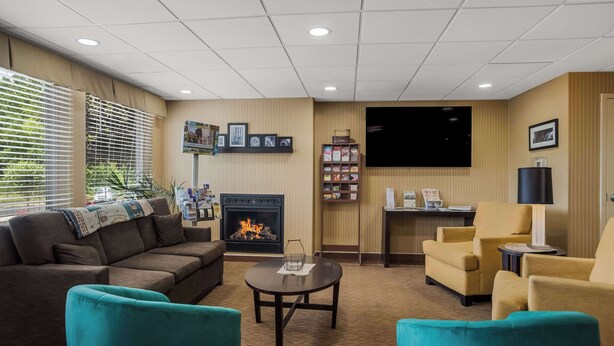 A cozy living room with a fireplace, comfortable seating, a flat-screen TV, and a small bookshelf. - Quality Inn & Suites Chambersburg Northeast (Chambersburg)