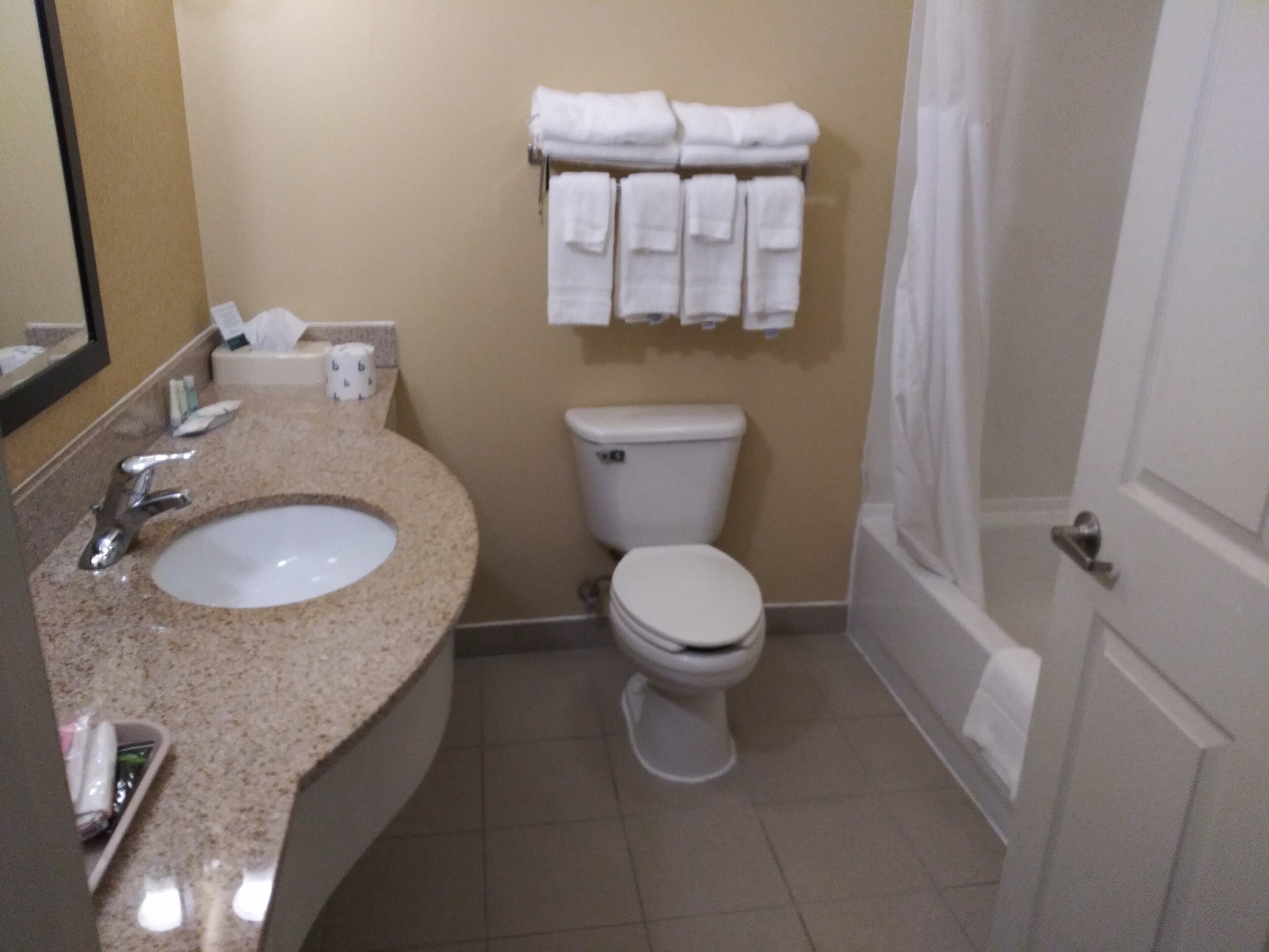 Ein Badezimmer mit Waschbecken, Toilette und einem Handtuchhalter mit Handtüchern.