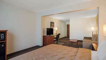A hotel room with a bed, a desk with a computer, a television, and a small table.