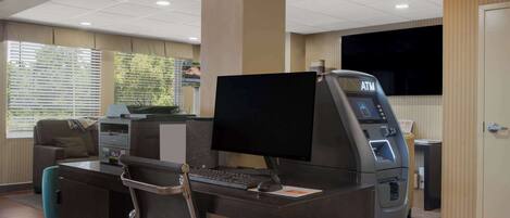 A reception desk with a computer, a printer, and an ATM.