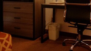 A hotel room with a desk, chair, and a lamp. There is a trash bin and a small table with a lamp on it. - American Inn of Liberal (Liberal)