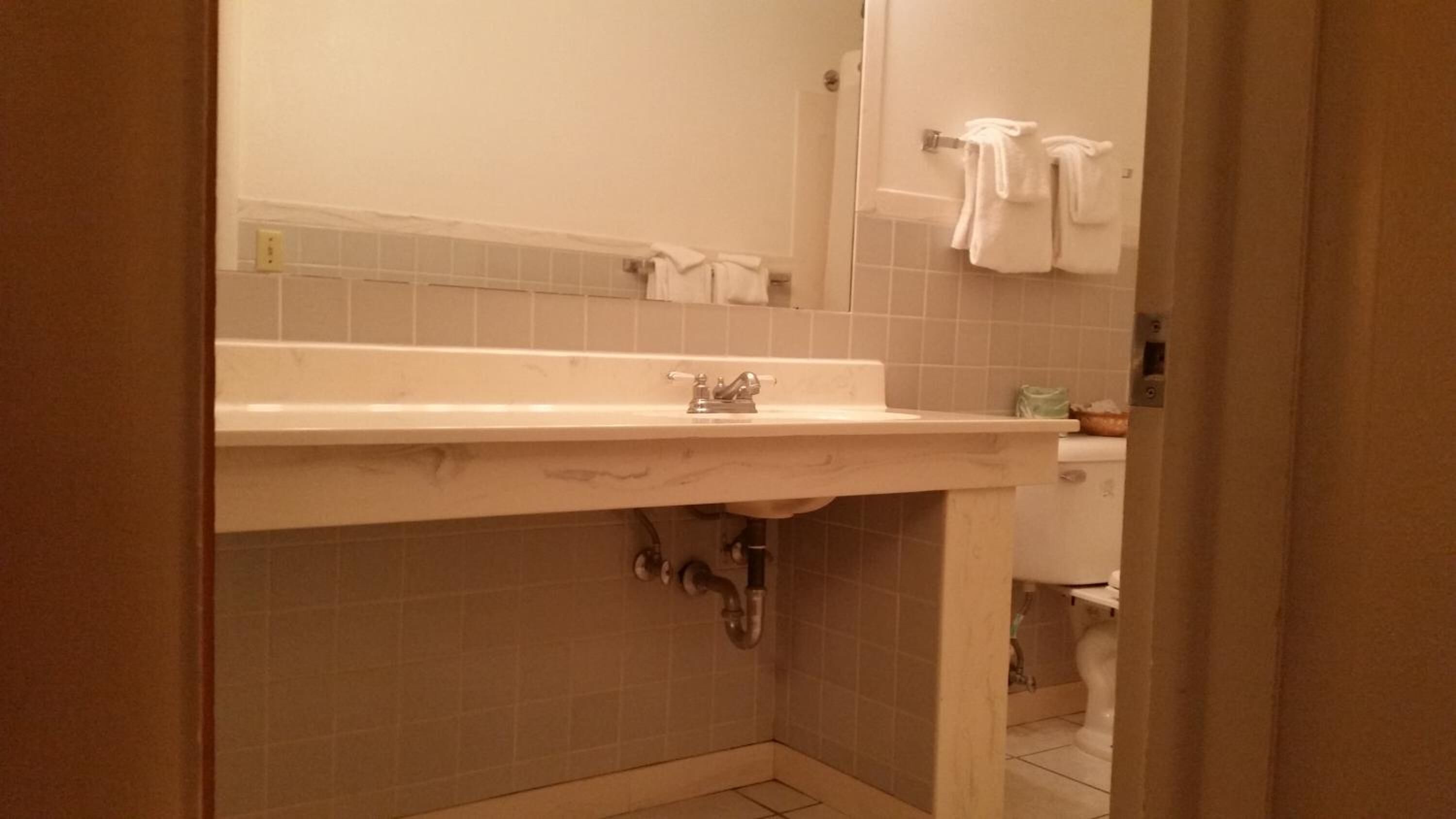 A bathroom with a white sink, a mirror, and a toilet.