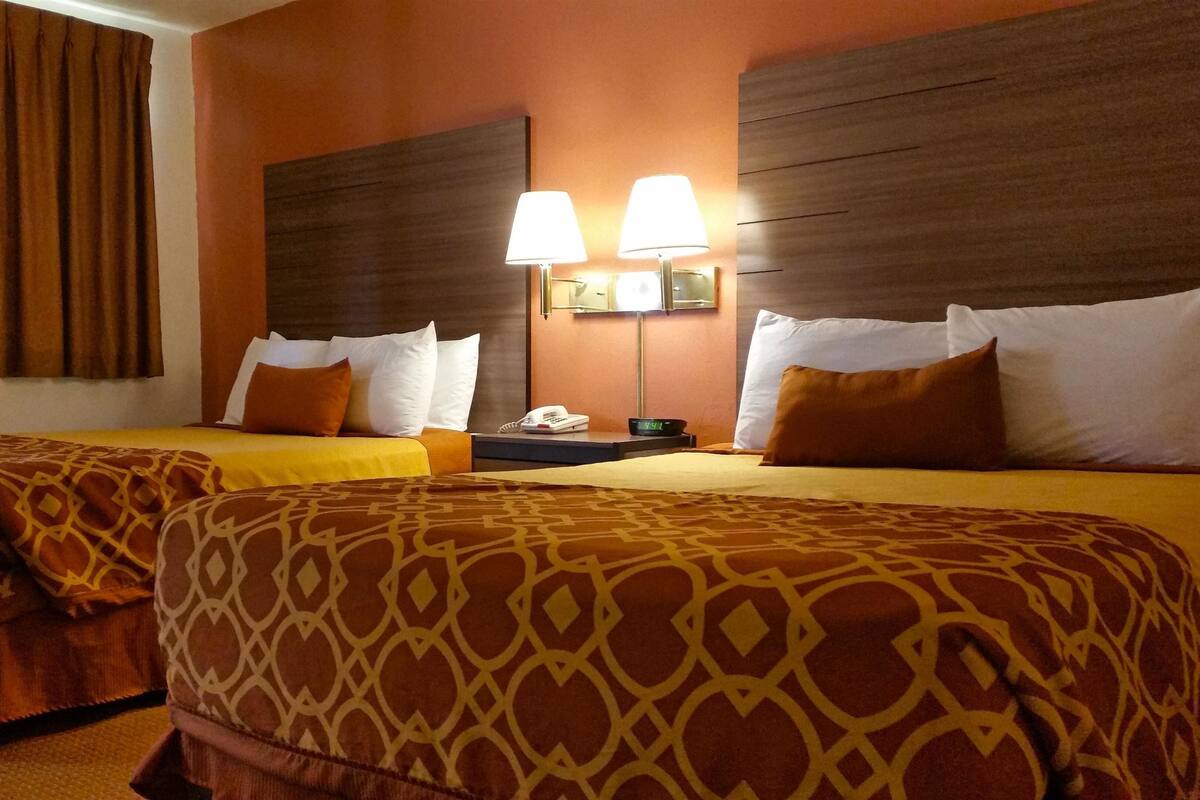 Camera d'albergo con due letti, un comodino, una lampada e un telefono.