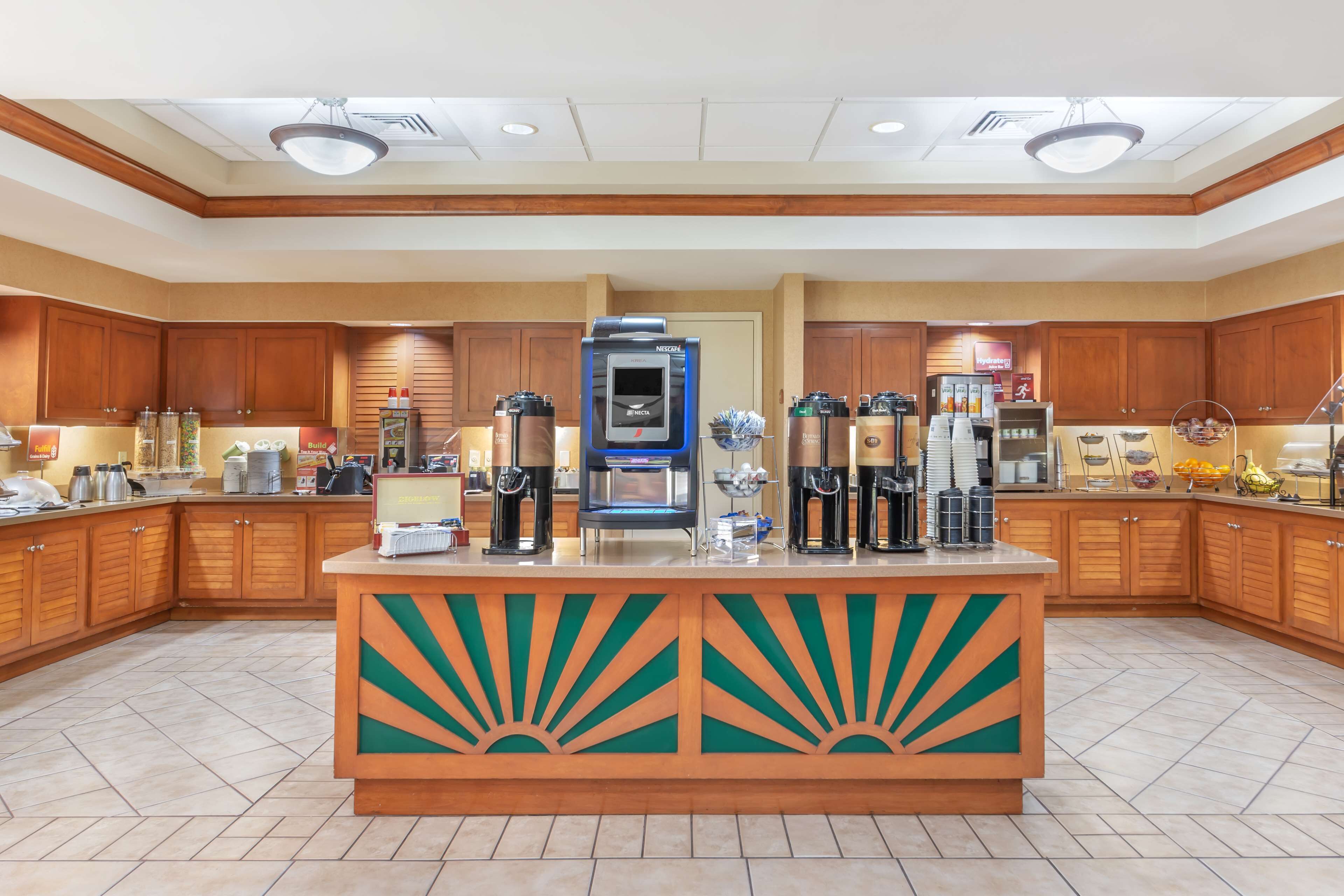 Una amplia cocina con armarios de madera, una isla central con estación de café y un microondas.