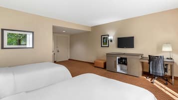 Habitación de hotel con dos camas, un escritorio, televisión y una pequeña kitchenette.