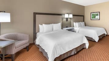 Habitación de hotel con dos camas, un sofá, un escritorio y una lámpara.