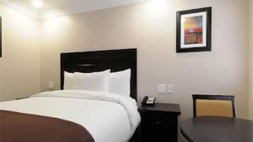 Habitación de hotel con cama, mesita de noche, una silla y un cuadro en la pared.