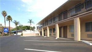 A motel with a parking lot, a covered walkway, and a building with balconies.
