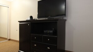 A dark wooden entertainment center with a flat-screen TV, a coffee maker, and a DVD player.