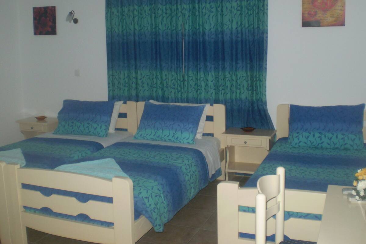 Una habitación con dos camas, una mesita y una silla.