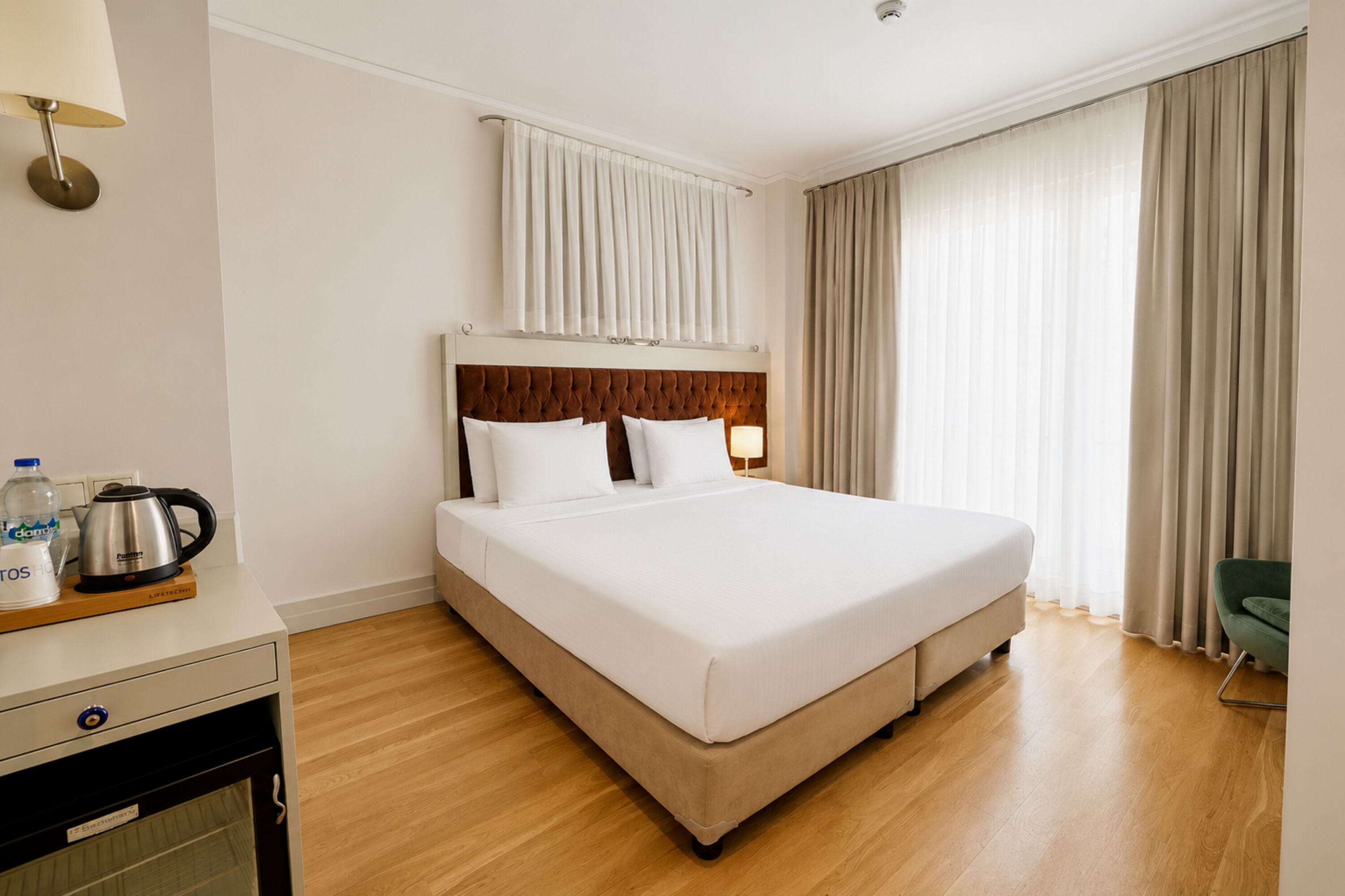Ein Hotelzimmer mit Bett, Nachttisch, Lampe, Wasserkocher und Stuhl.