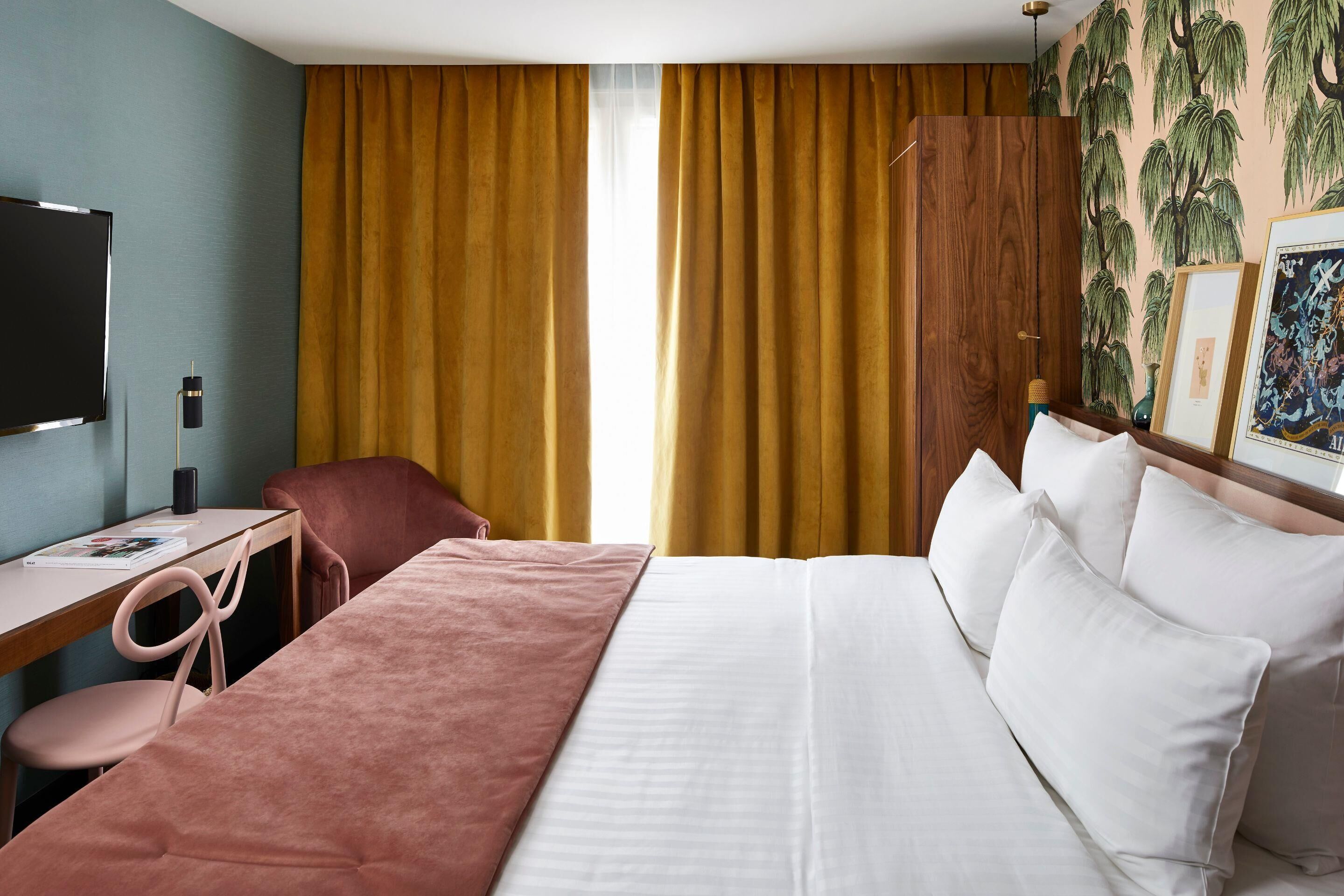 A hotel room with a bed, a desk, a chair, and a television.