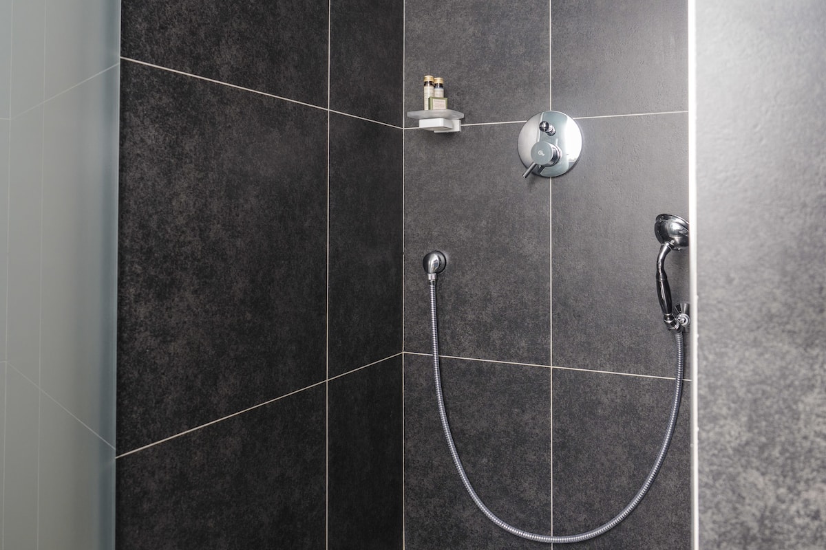 Une douche moderne équipée d’un pommeau de douche à main et d’un pommeau de douche fixe fixé au mur.