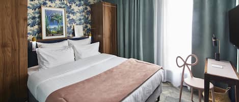 A hotel room with a large bed, a desk, a chair, a TV, and a framed picture on the wall.
