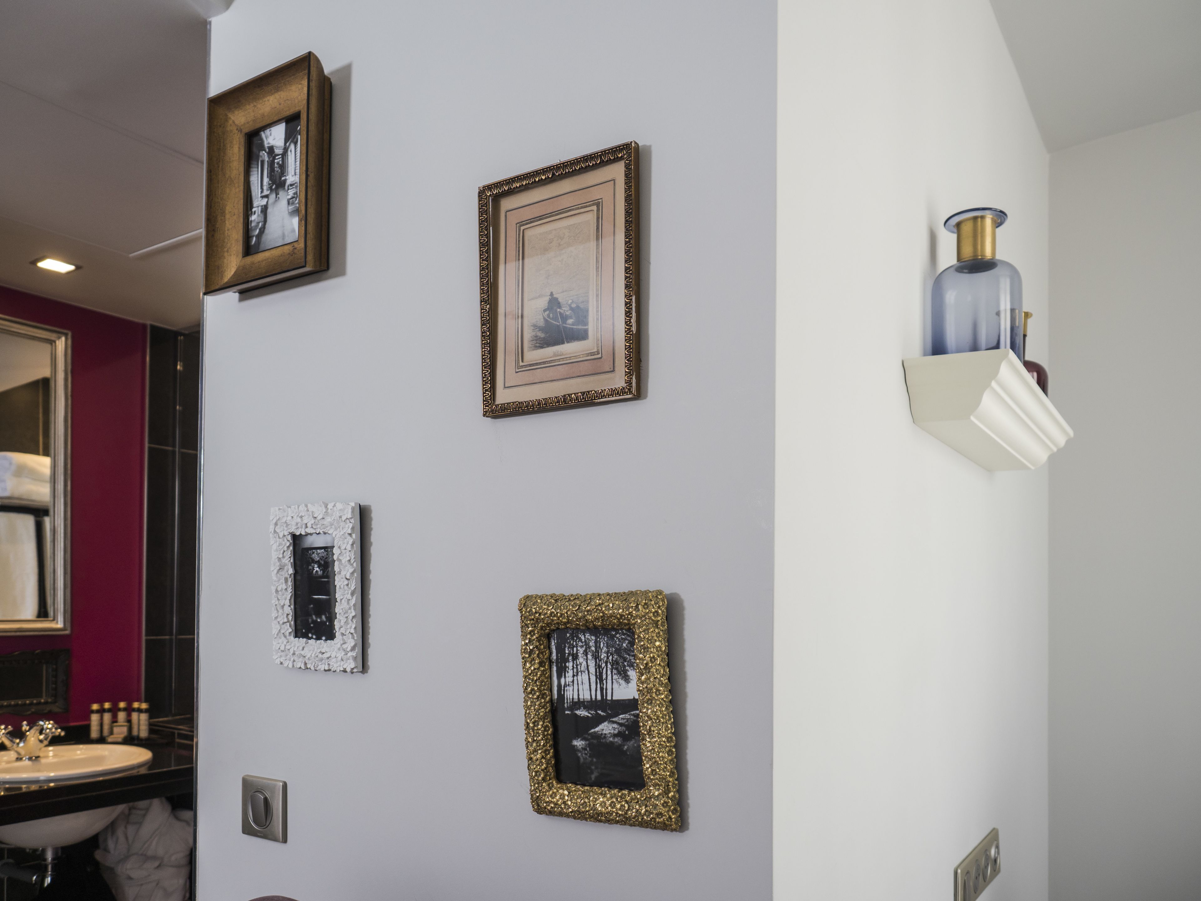 A bathroom with a white sink, a mirror, and four framed pictures on the wall.