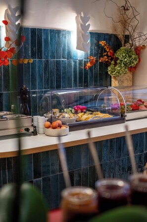 A buffet area with a variety of food items, a coffee station, and a decorative plant arrangement. - Hotel Taylor (Paris)