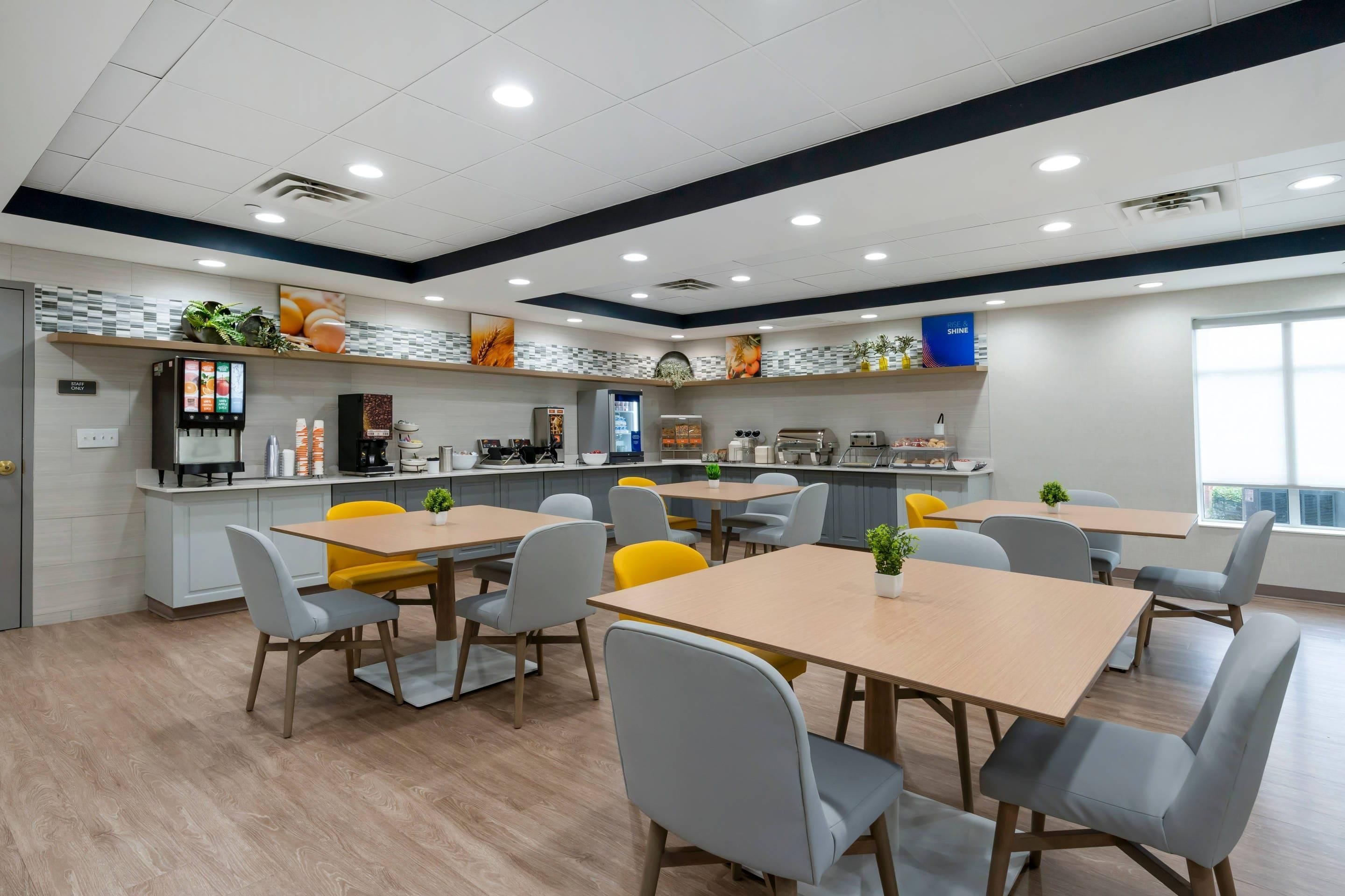 Un comedor moderno con varias mesas y sillas, una barra de cocina y un letrero que indica acceso solo para personal.