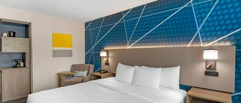 Una habitación de hotel con una cama grande, una mesita de noche, una silla y una pared con un diseño geométrico.