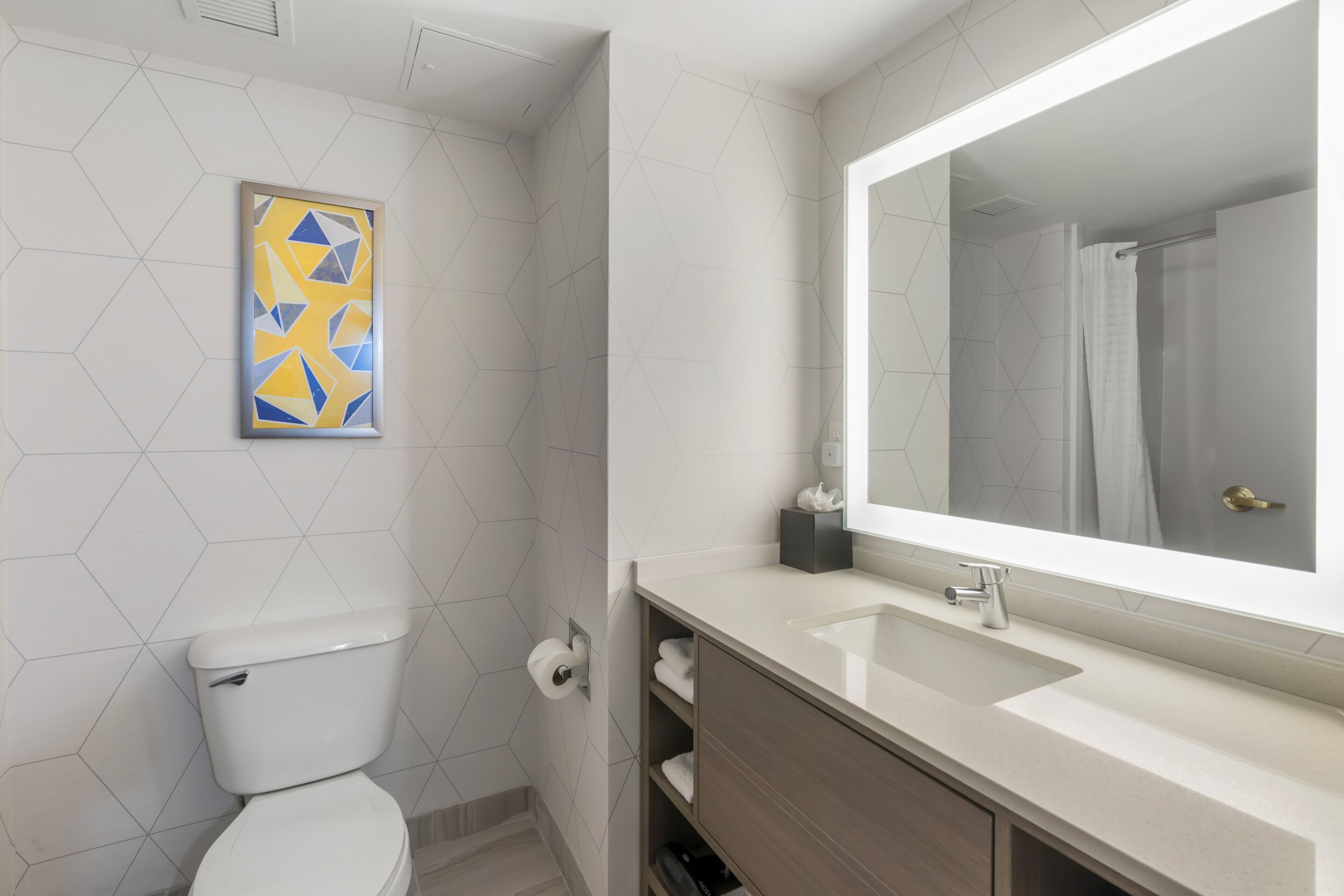 A modern bathroom with a toilet, sink, and mirror.