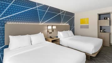 Une chambre d’hôtel avec deux lits, une table de chevet avec un téléphone, un mur orné d’un motif géométrique et une étagère avec divers objets.