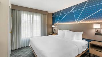 Una habitación de hotel con una cama grande, un escritorio, un teléfono y una pared con diseños geométricos.