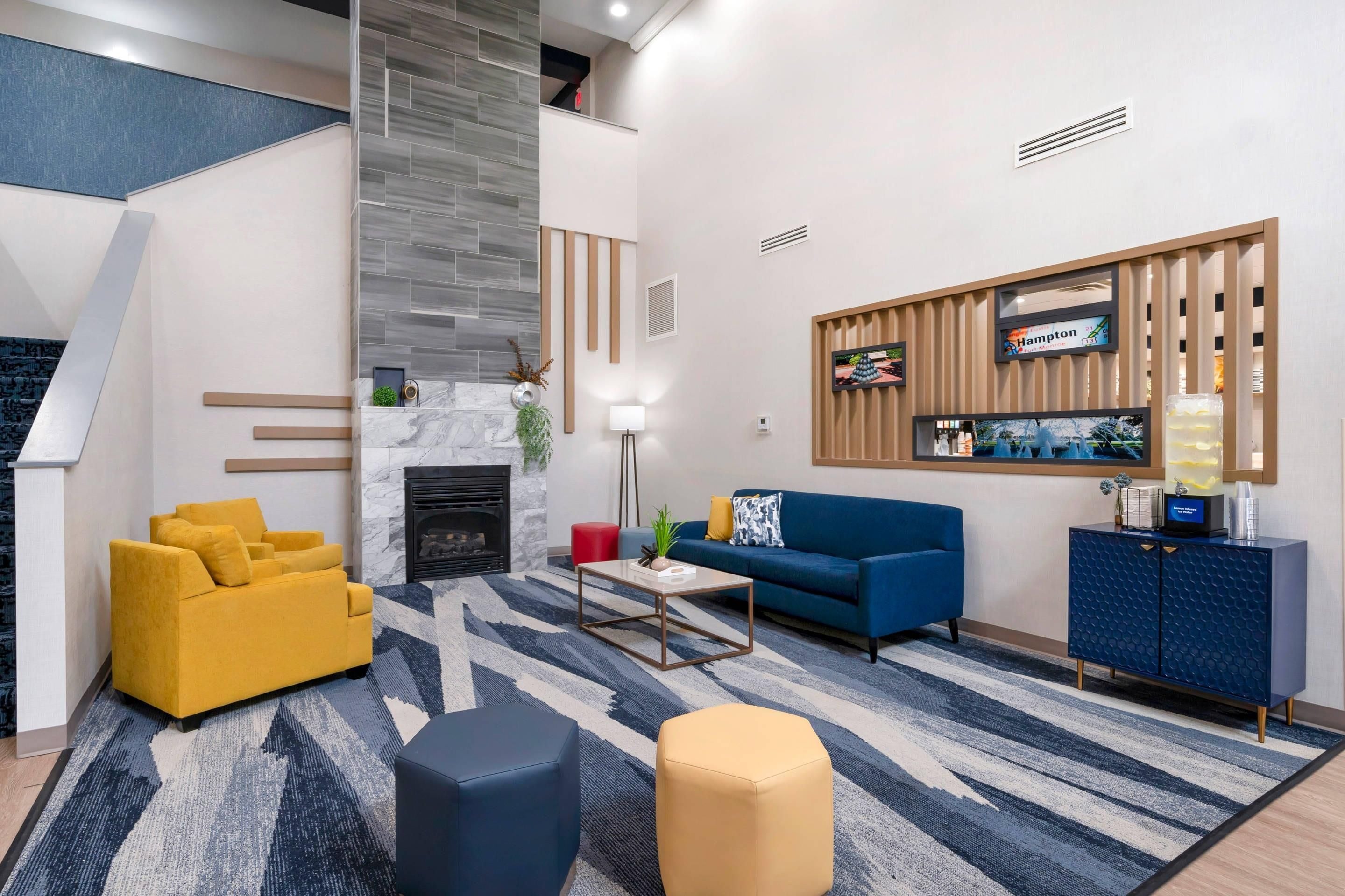 Un salon moderne avec une cheminée, un canapé, une table basse et un téléviseur fixé sur un panneau en bois.