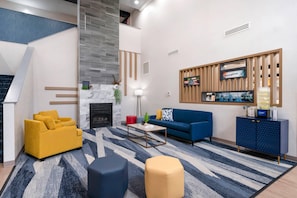 A modern living room with a fireplace, a sofa, a coffee table, and a TV mounted on a wooden panel. - Comfort Inn & Suites Hampton near Coliseum (Hampton)