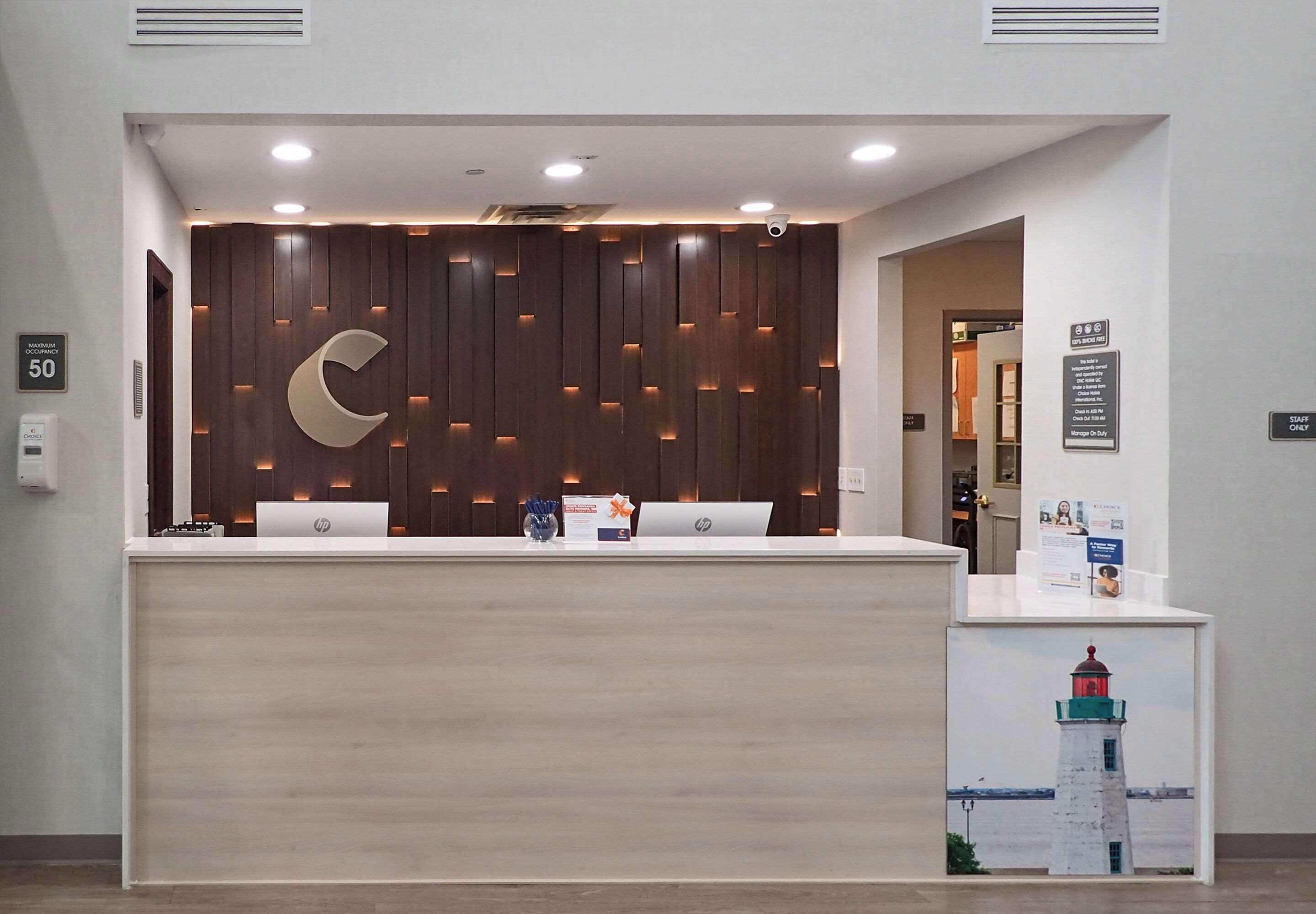 A reception desk with a wooden panel design, two HP laptops, and a sign indicating a staff-only area.