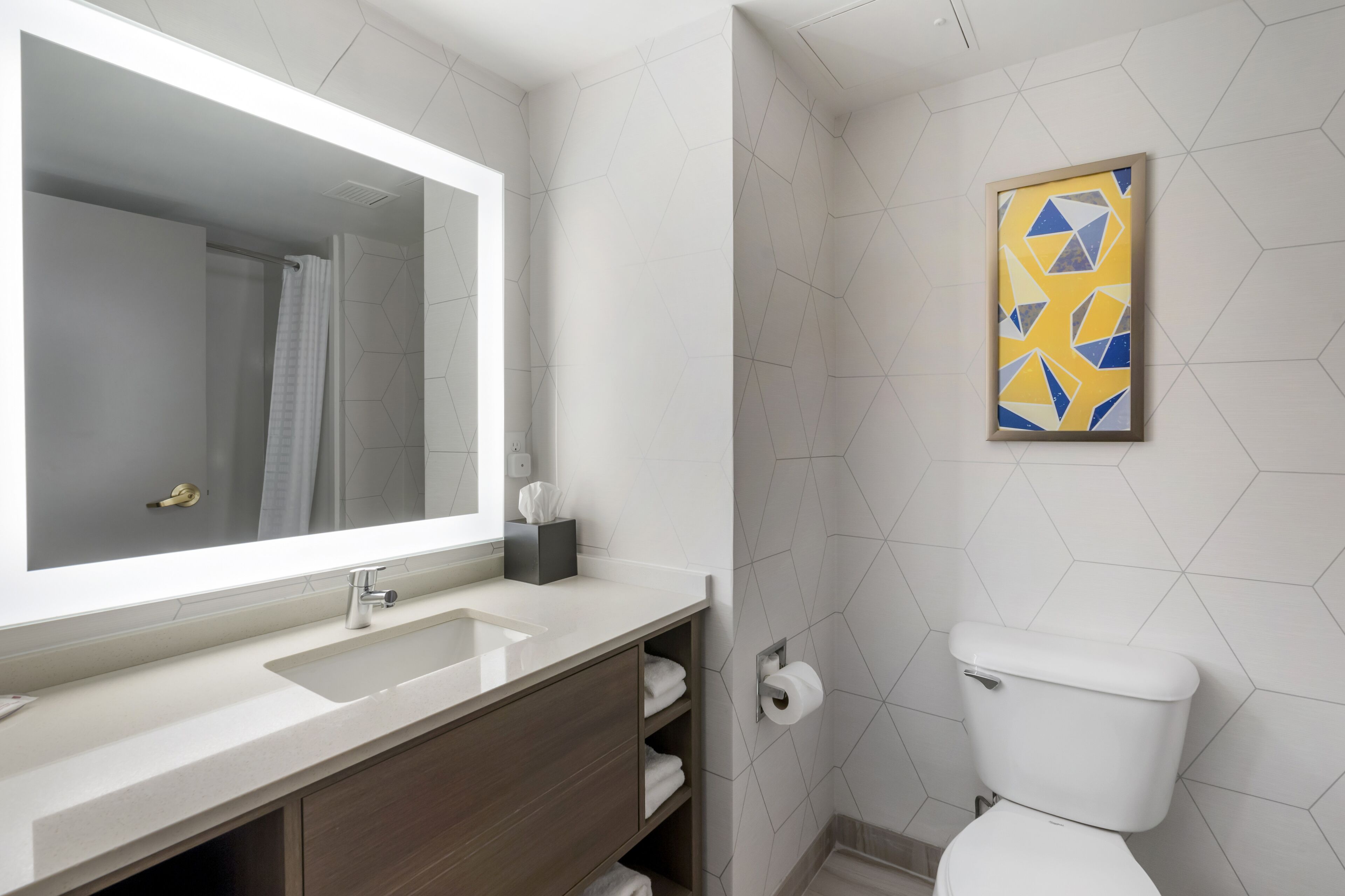 Un baño moderno con un espejo grande, un lavabo, un inodoro y una ducha.
