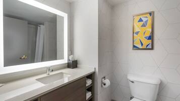 Un baño moderno con un espejo grande, un lavabo, un inodoro y una ducha.