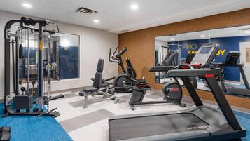 A gym with cardio equipment, weight machines, and a mirrored wall.