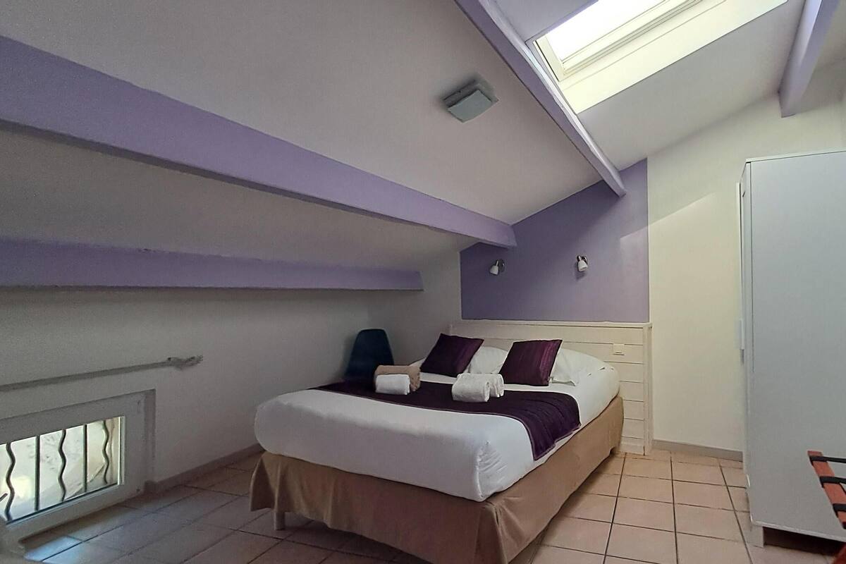 A bedroom with a bed, a window, a radiator, and a wardrobe.