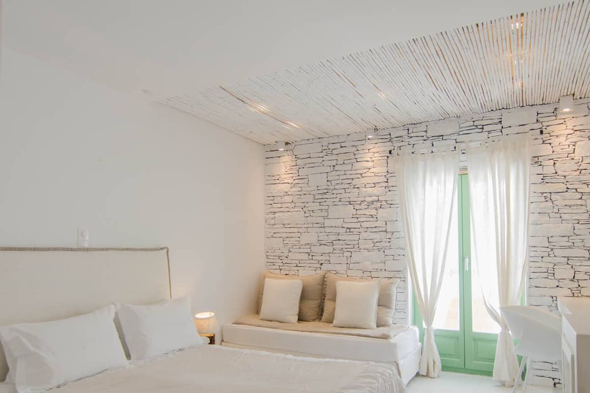 Un dormitorio con una cama grande, un sofá, un escritorio y una ventana con cortinas.