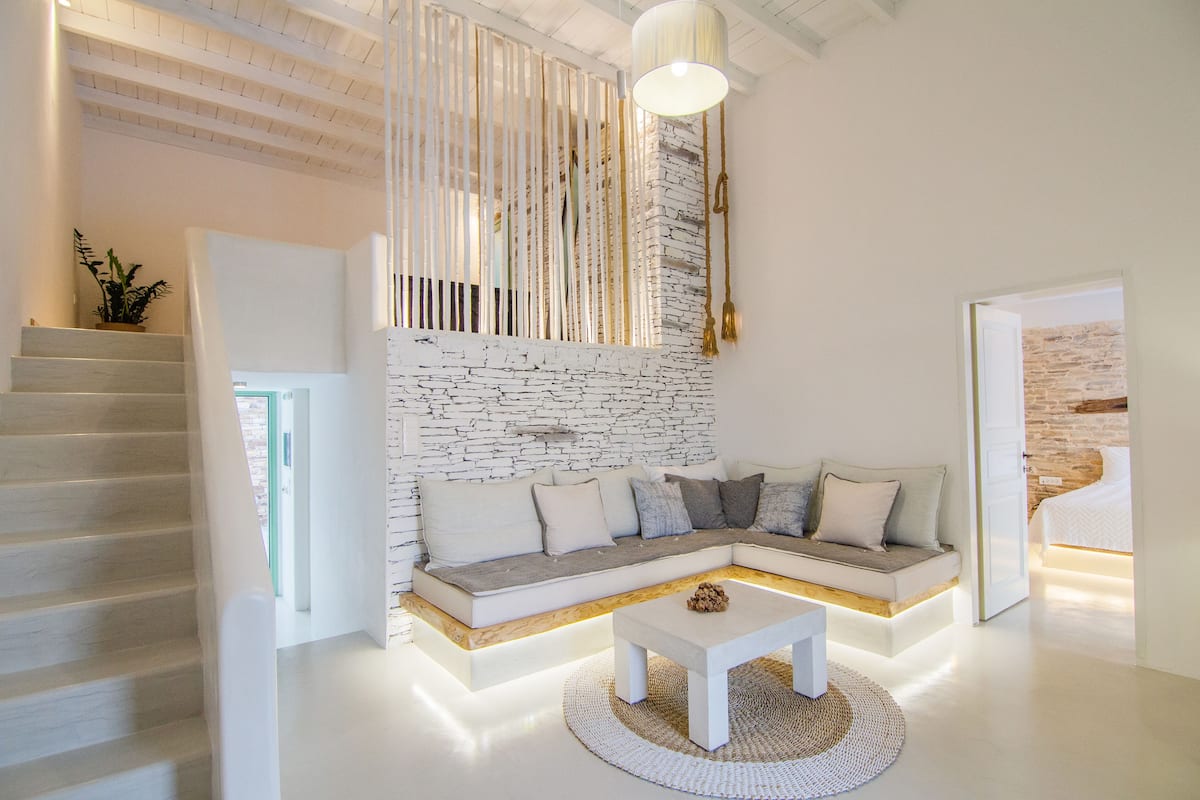 Una sala de estar moderna con una pared de ladrillo blanco, un sofá modular, una mesa de centro y una escalera.