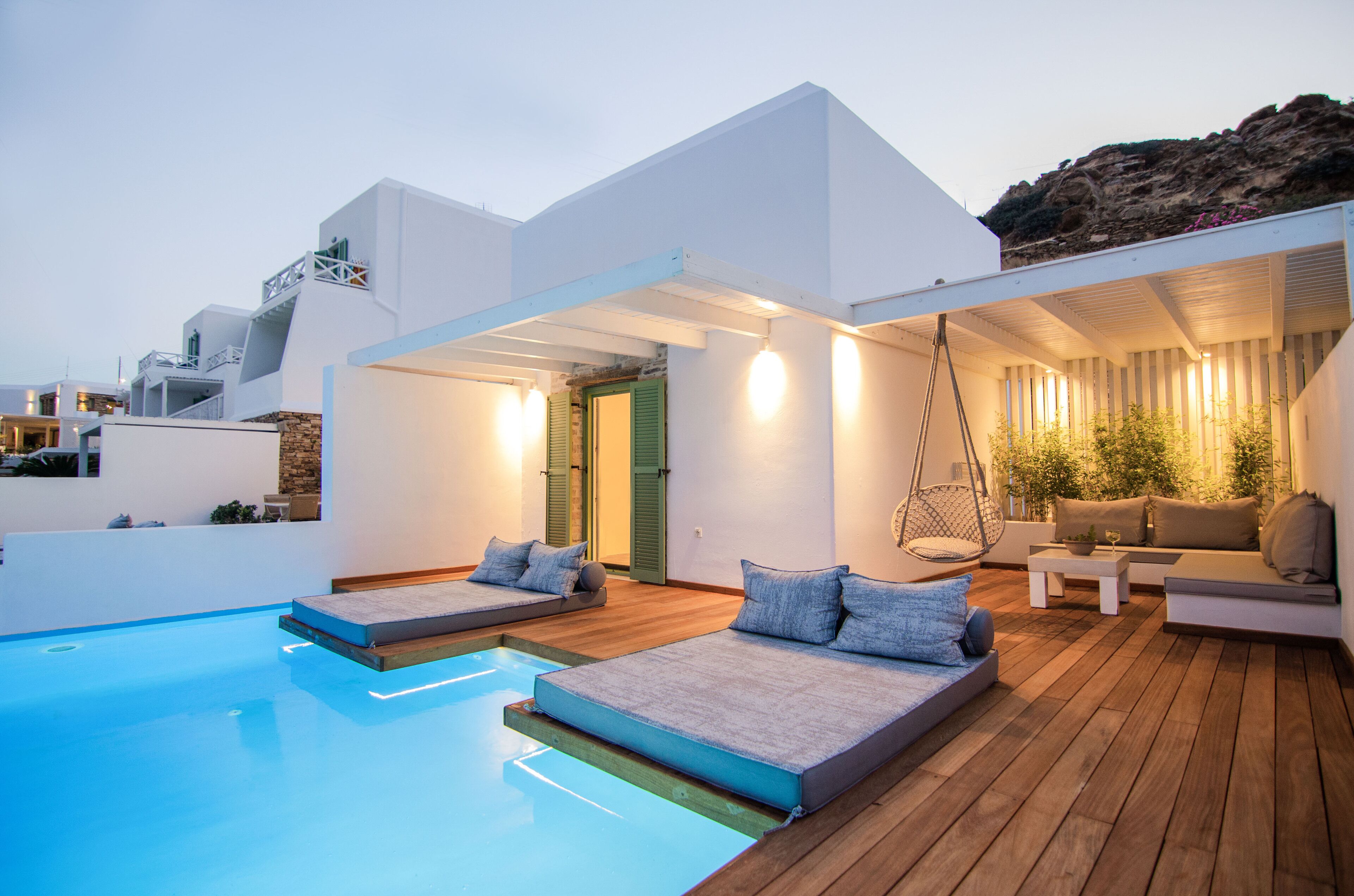 Un espace piscine extérieur moderne, doté de deux chaises longues et d’un coin salon.