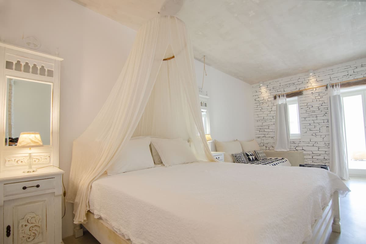 Un dormitorio con cama a dosel, cómoda con espejo y pared con diseño de piedra.