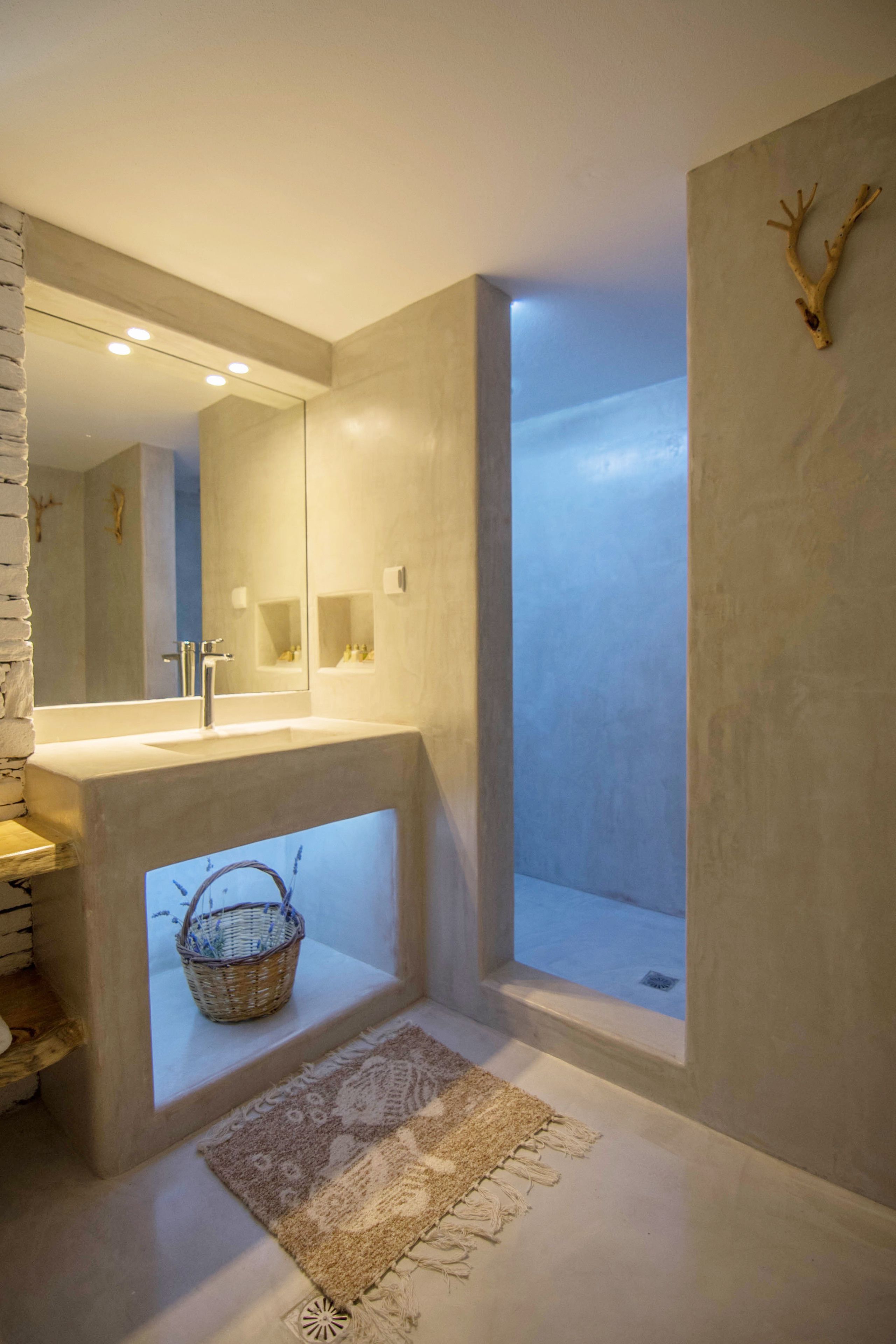 Un baño moderno con un espejo grande, un lavamanos y una ducha.