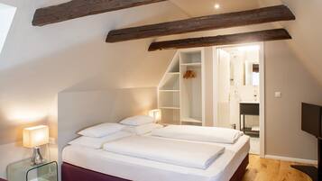 A bedroom with a large bed, a glass bedside table, a wardrobe, and a TV.
