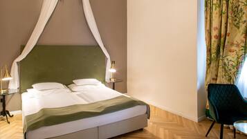 Cama bem arrumada com cabeceira verde, duas luminárias de apoio e cortina florida.