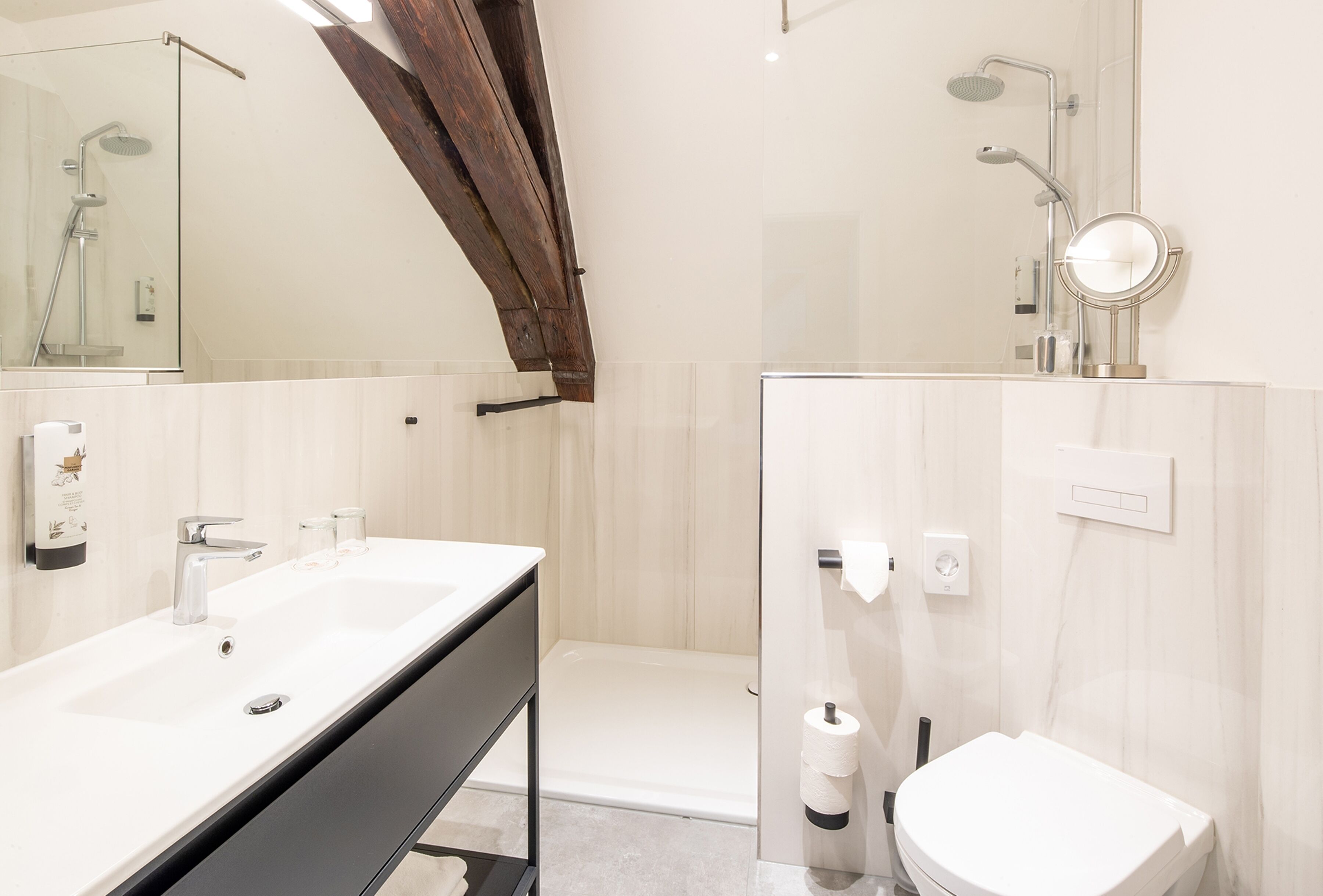 A modern bathroom with a large mirror, a bathtub, a toilet, and a sink.