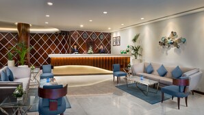 A modern reception area with a wooden reception desk, a sofa, and chairs.