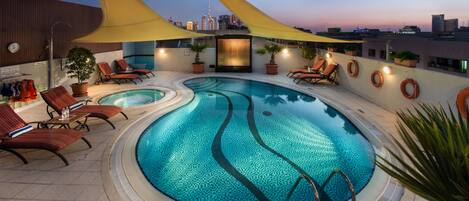 Una piscina al aire libre, sombrillas, sillones reclinables de piscina