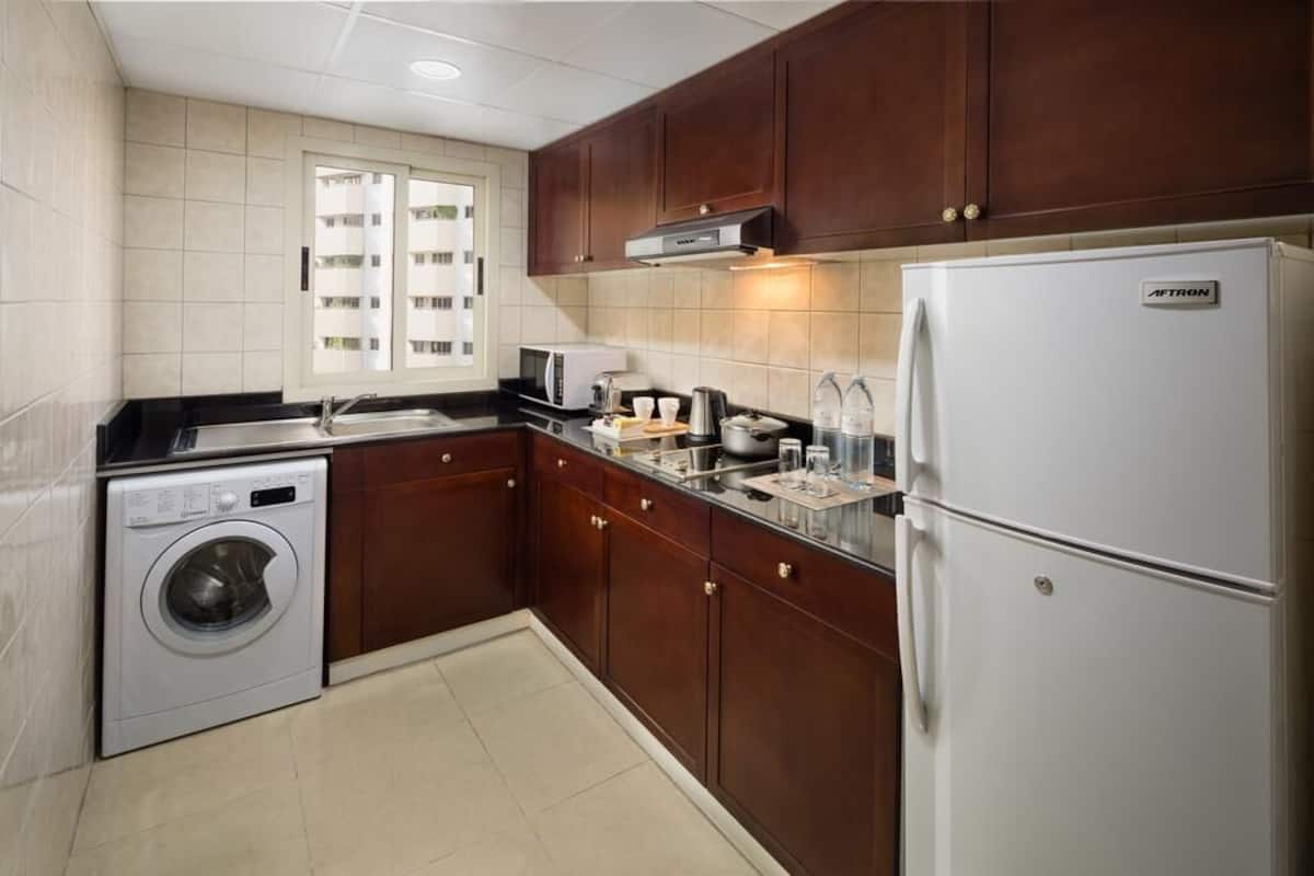 A compact kitchen with a washing machine, microwave, toaster, and a refrigerator.