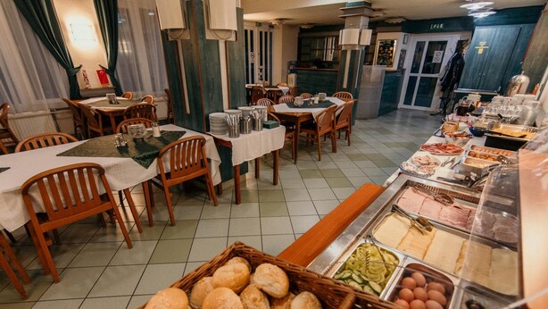 A buffet setup with various food items and a basket of bread rolls. - Tisza Sport Hotel (Szeged)