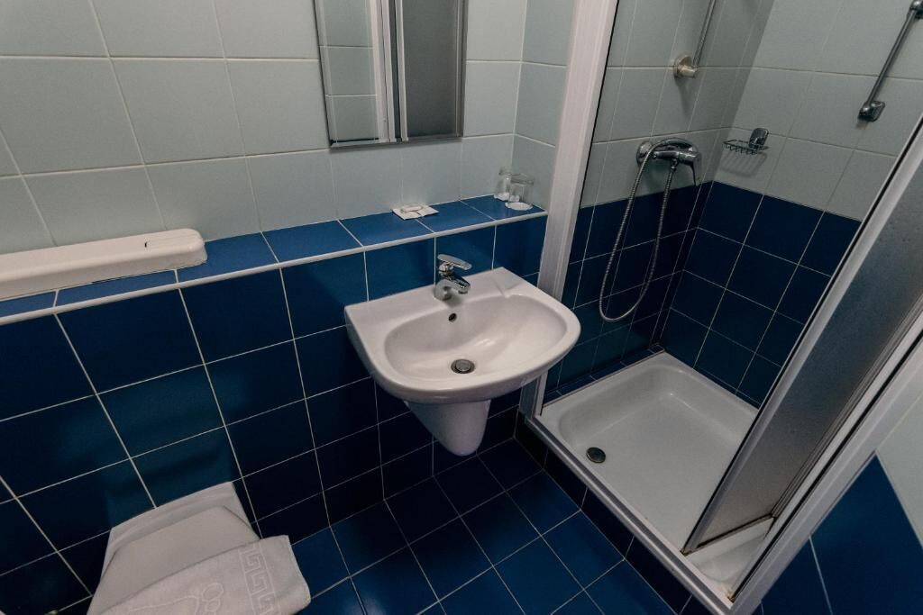 Une salle de bain avec un lavabo blanc, une douche et des murs recouverts de carreaux bleus.