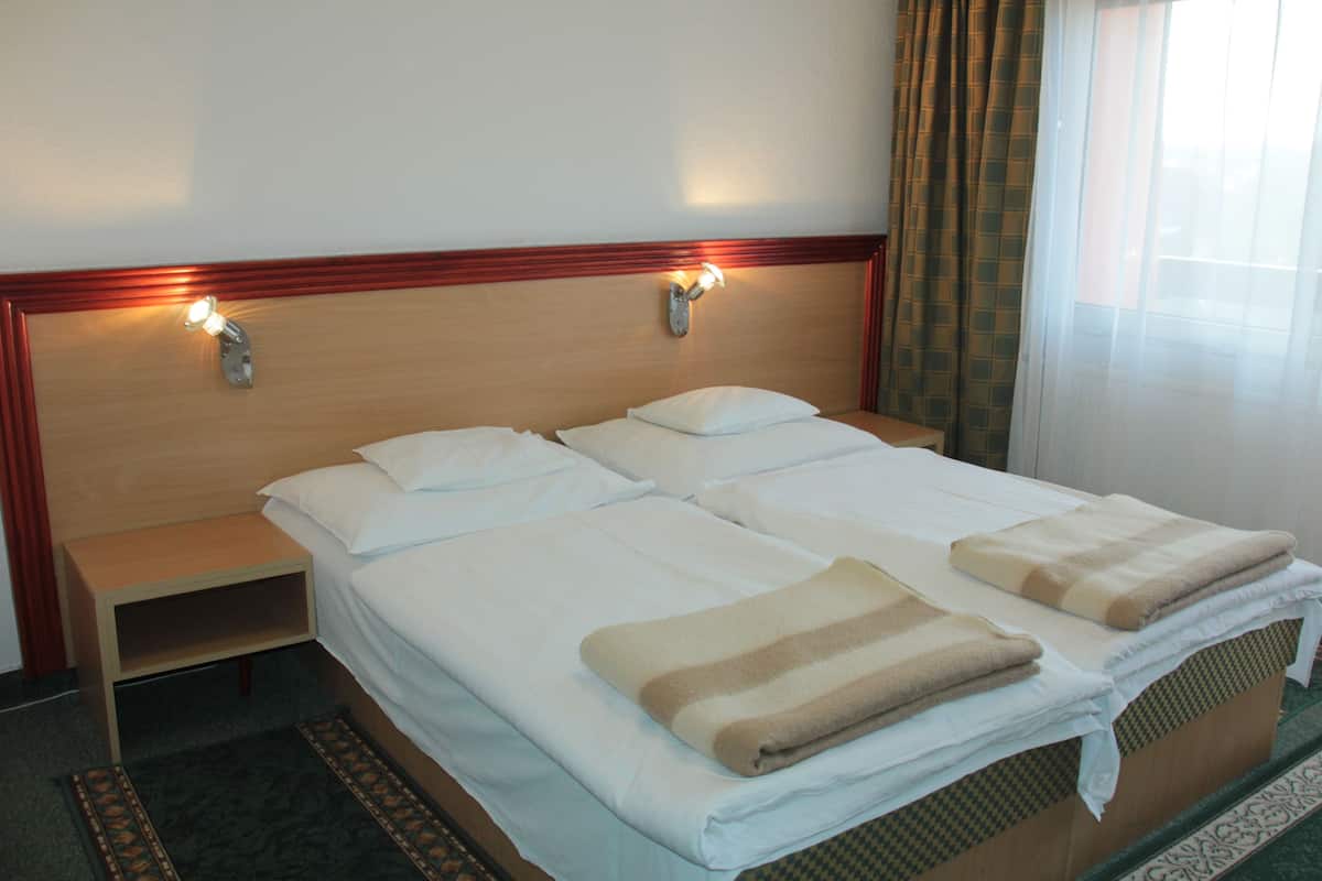 Una cama doble con dos almohadas, una mesita de noche y un mueble auxiliar.