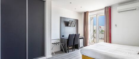 Een moderne hotelkamer met een bed, bureau, stoelen en een schuifdeur.
