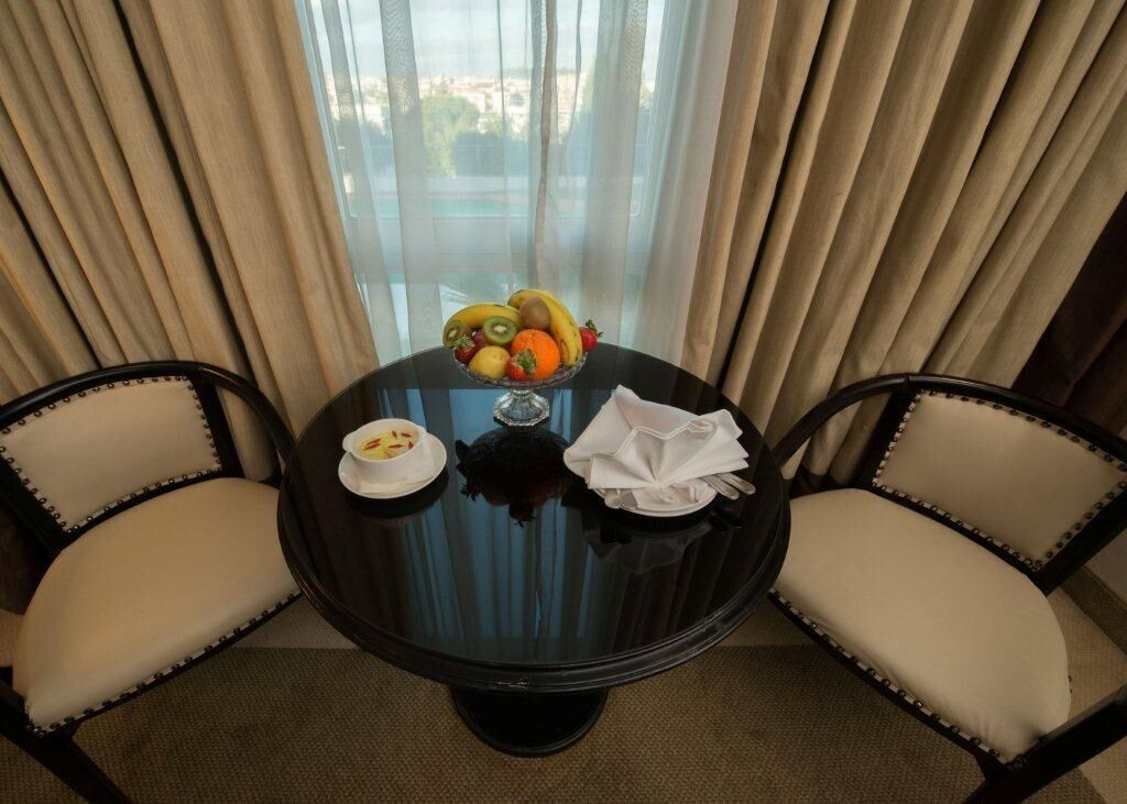 A dining table with a fruit bowl, a white plate, and a napkin. Two chairs are positioned around the table.