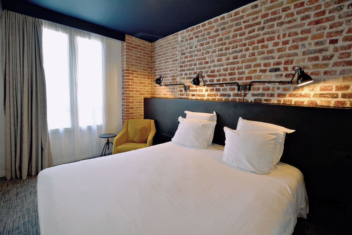 Una camera d'albergo con un letto grande, un muro in mattoni e un tavolino.